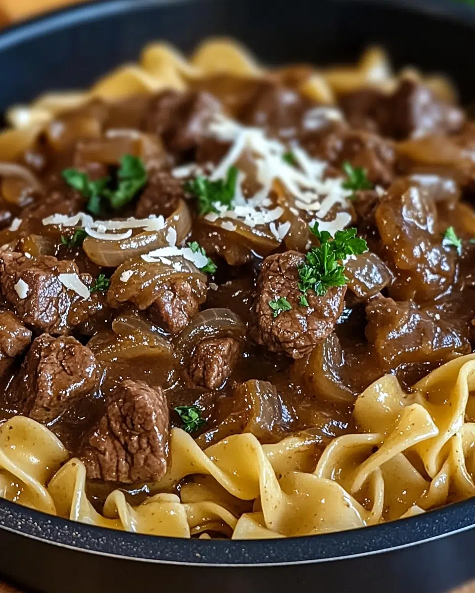 Tender slow cooker beef and noodles in rich onion gravy served over egg noodles