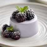 Plated No-Bake Lavender Posset with Blackberries garnished with mint on a white ceramic plate